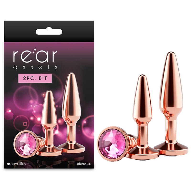 Rose gold butt plugs with pink gemstones and 'rear assets' packaging on a white background