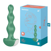 A product image showcasing the Satisfyer Lolli-Plug 2 Green Butt Plug. The green, silicone anal plug features a series of bulbous shapes perfect for reaching those anal pleasure points with rolling vibration. The packaging, displaying an illustrated profile of a face and the product name, is also visible.