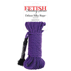 The Fetish Fantasy Series Deluxe Silky Rope - Purple by Pipedream is a packaged rope ideal for Shibari-style bondage. This neatly coiled purple rope features a black tape tie on one end and a black tassel on the other. The packaging prominently displays the brand name in red and black.
