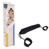 Image of a versatile pleasure device, the Pivot Positioning Bar with attached cuffs. Designed for intimate use, it’s shown next to its packaging, which displays illustrations of possible uses. The bar features a cushioned middle section with adjustable cuffs on both ends.