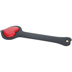 The OUCH! Milan Collection - BDSM Paddle, made from bonded leather, showcases a black exterior with a red heart-shaped pad at one end, ideal for playful spanking in adult scenarios. A small rivet decorates the handle's base. Displayed against a white background, this paddle adds an elegant touch to any BDSM set.