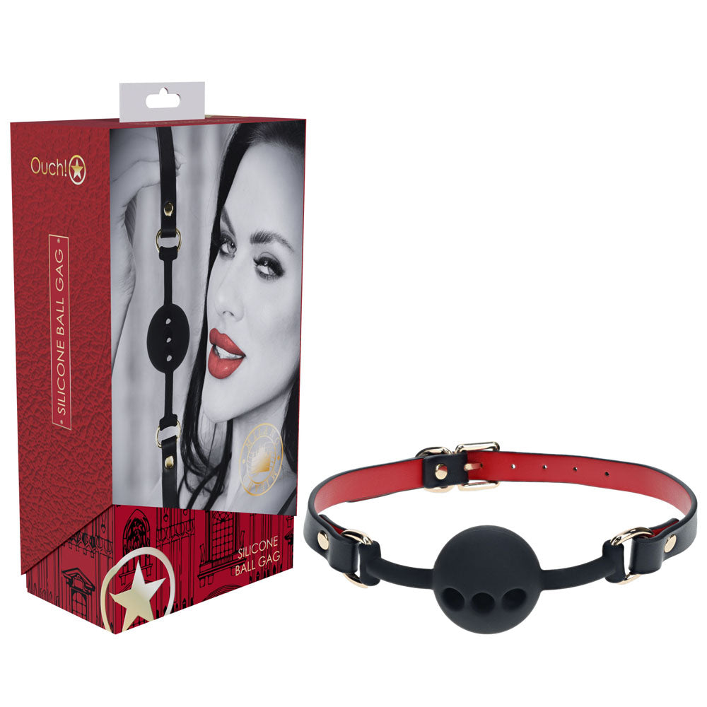 A black silicone ball gag with a red and black adjustable strap from the OUCH! Milan Collection - Silicone Ball Gag lineup is shown next to its packaging. The package features a close-up image of a person with red lips, partial face visible, and the text "OUCH! Silicone Ball Gag." Perfect for your next naughty game.