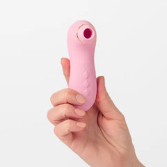 Pink handheld electronic device held in a hand against a light gray background