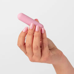 Hand holding a pink cylindrical object against a light gray background