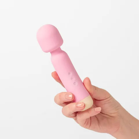 Pink handheld massager held in a hand against a white background