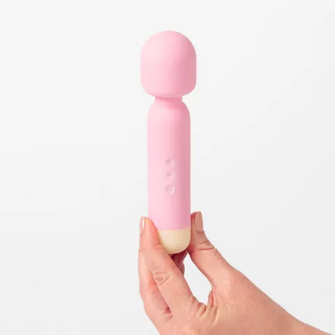 Pink handheld massager held in a hand against a white background