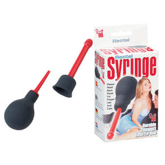 The image shows the Seven Creations Rectal Syringe Douche, a black and red unisex rectal syringe with an attachable douche nozzle, along with its packaging. The syringe features a rubber bulb and a detachable nozzle. The box displays the product name "Seven Creations Rectal Syringe Douche" and includes usage instructions as well as illustrations of a person using the product on the front.