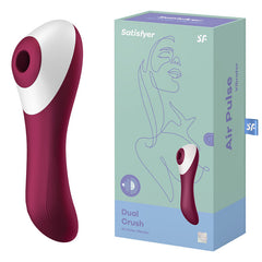 The image features a Satisfyer Dual Crush in dark red and white next to its box. The light blue box showcases an illustration of a woman's face along with the product name. The vibrator, aimed at clitoral stimulation and G-spot arousal, boasts a contoured design complemented by a smooth, ergonomic handle.