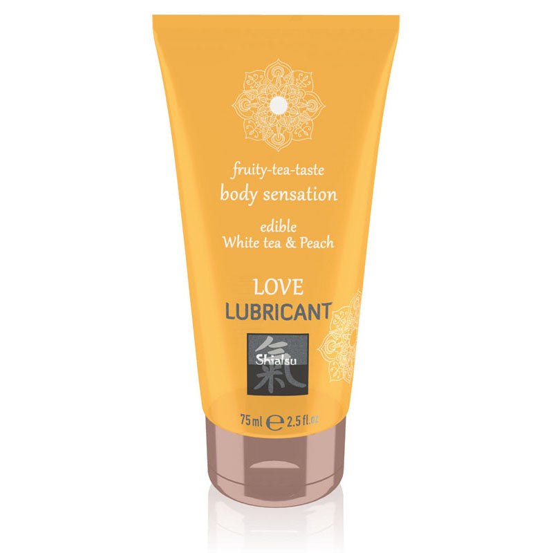 A vibrantly designed 75ml (2.5 fl. oz) tube of SHIATSU Love White Tea & Peach Water-based Lubricant, featuring a delectable edible White Tea & Peach flavor for a fruity-tea-taste body experience. The orange tube is adorned with an intricate mandala design and carries the brand name "Shiatsu" prominently on its label.