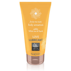 A vibrantly designed 75ml (2.5 fl. oz) tube of SHIATSU Love White Tea & Peach Water-based Lubricant, featuring a delectable edible White Tea & Peach flavor for a fruity-tea-taste body experience. The orange tube is adorned with an intricate mandala design and carries the brand name "Shiatsu" prominently on its label.