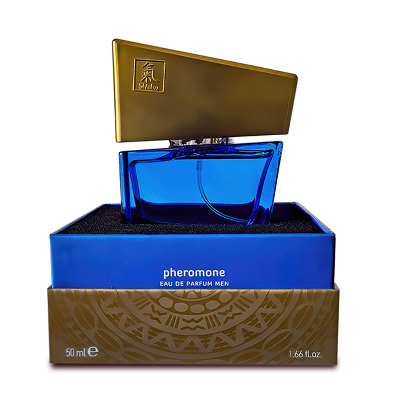 A 50 ml bottle of Shiatsu Pheromone Eau De Parfum Men - Dark Blue is displayed, renowned for its powerful sexual attractants. The glass bottle, colored dark blue, has an angular gold cap and rests in an open blue and gold box that features intricate designs and clear text indicating product information.