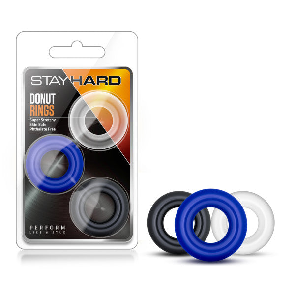 A plastic package labeled "Stay Hard - Donut Rings" contains three circular rubber rings in black, blue, and clear. The text on the package mentions "Super Stretchy, Skin Safe, Phthalate Free." These cock rings are designed to increase stamina. The three rings are shown next to the package as well.