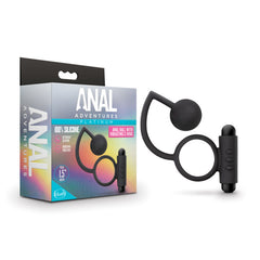 A product image of the "Anal Adventures Platinum Anal Ball Butt Plug & Vibrating Cock-Ring" set, showcasing a silicone anal ball for prostate stimulation attached to a vibrating C-Ring, displayed beside its packaging. The packaging highlights features such as a 100% silicone tag and a 1.5-inch ball diameter.