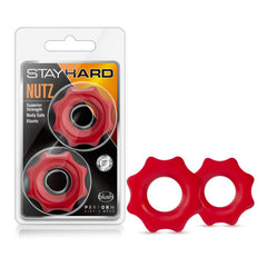 The package, marked "Stay Hard Nutz," contains two red, gear-shaped cock rings with a central hole. Promoting attributes like "Superior Strength," "Body Safe," and "Elastic," the durable, phthalate-free rings are also displayed outside of the package.