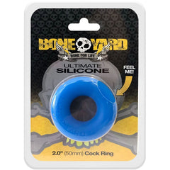 The packaging of the Boneyard Ultimate Silicone Cock Ring Blue features an exposed section of the blue silicone ring branded with "Boneyard Ultimate Silicone." An arrow points to this section with the text "FEEL ME!" to showcase its durable stretch. The size is specified as 2.0" (50mm), and the background displays skull and bone designs.