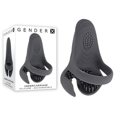 The Gender X UNDERCARRIAGE Cock Ring, made from black silicone, is showcased beside its packaging. This rechargeable intimate toy features a textured surface, a looped handle, and a contoured design for ergonomic use. Enjoy multiple vibrating speeds with this waterproof and submersible accessory.