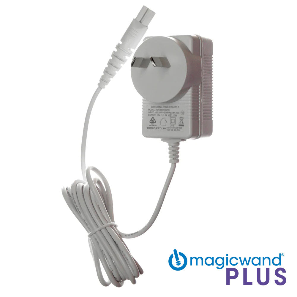 Image of a white Magic Wand Plus - Power Cord with an attached power cable. The replacement power supply features a plug, electrical information, and symbols on its front. The text "magicwand PLUS" is at the bottom right corner next to a blue logo.