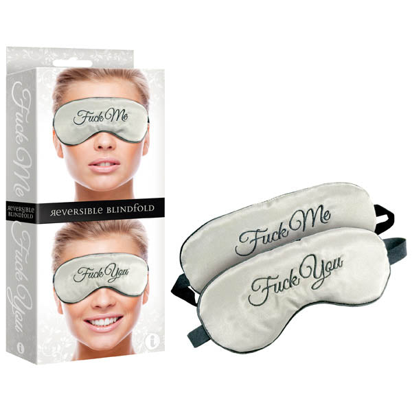 The Fuck Me/Fuck You Reversible Blindfold is displayed both inside and outside its packaging. One side of the silk blindfold features the phrase "Fuck Me," while the other side displays "Fuck You," both embroidered in elegant script. The packaging includes an image of a smiling person wearing the blindfold.