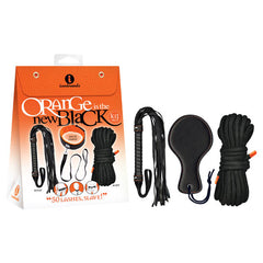 An adult novelty set in orange and black packaging with "Orange Is The New Black Kit #3 - 50 Lashes, Slave! - Bondage Kit - 3 Piece Set" written on it. This BDSM kit includes a whip, two lengths of rope, and a paddle. The packaging also features smaller images of the items inside and the brand logo "iconbrands" at the top.