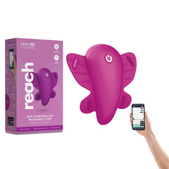 A purple, butterfly-shaped wearable vibe called the "Love Distance REACH Panty Vibrator" is displayed next to its packaging. A hand holds a smartphone showing the control app for the device. The box emphasizes powerful vibrating functions and wireless remote control features.