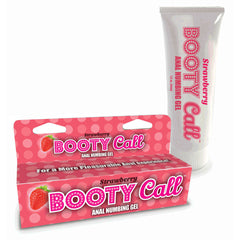 A tube and a box of "Booty Call Anal Numbing Gel - Strawberry" are displayed. The white tube with pink text and the pink box with white dots both feature the same product name and a strawberry graphic. The box reads, "For a More Pleasurable Anal Play Experience!