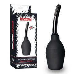 A boxed product labeled "Bondage Fetish Deluxe Douche" from Lovetoy is shown. To the right of the box, you can see the actual anal douche, which features a bulbous black base and a long, slender nozzle. Both the packaging and the product have a sleek, modern design tailored for adult use.