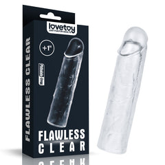 A clear silicone toy from the LOVETOY Shameless Clear series, named the Flawless Clear Penis Sleeve 1'' - Clear 2.5 cm Penis Extender Sleeve, sits beside its black packaging. The packaging prominently displays the brand name "lovetoy" along with the slogan "Just Fun for Adults," and includes the text "Flawless Clear," "+1 inch," and "Phthalate-Free." The super-realistic sculpted toy has a lifelike shape.