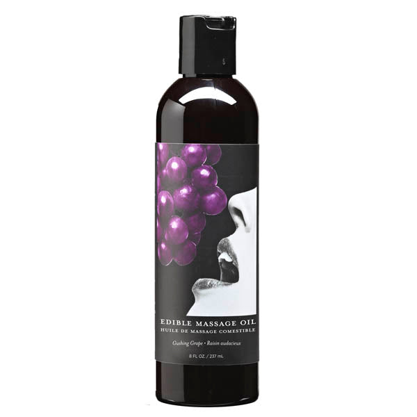 A black bottle with a black flip-top lid contains vegan edible massage oil. The label features an image of a woman's face with her mouth open, approaching a bunch of purple grapes. Text on the label reads "Edible Massage Oil - Gushing Grape Flavoured." The bottle is 237 ml / 8 fl oz.