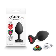 The image features the Glams Xchange Heart - Medium, a black silicone medium-sized butt plug with a heart-shaped base, embellished with a red gem. Accompanying it are two extra interchangeable gems in crystal clear and multicolor variants. Crafted from premium-grade silicone, this stylish accessory is presented in a box that showcases the brand name "Glams Xchange" along with images of the butt plug and its interchangeable gems.