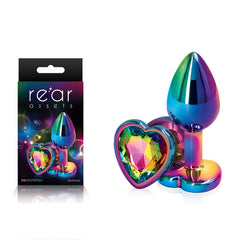 A Rear Assets Multi Coloured Heart Butt Plug, a lightweight and chrome-plated anal toy featuring a heart-shaped gem in vibrant rainbow hues. On the left is its box, which includes an image of the plug and prominently displays the brand name "Rear Assets.