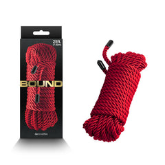A product image showcasing a coiled 7.6-metre red rope made from durable polyester fibre. The non-chaffing rope is displayed both inside black and gold packaging and coiled outside next to the packaging. The packaging features the brand name "Bound" written in bold letters, identifying it as the Bound Rope - Red - Red Bondage Rope.