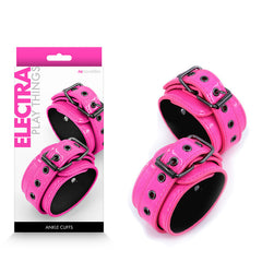 The image showcases the product packaging for NS Novelties' "Electra Ankle Cuffs - Pink." The bright pink ankle cuffs feature black trim, metal buckles, and comfortable neoprene lining. The predominantly white packaging includes a pink header and side text. The product is displayed both inside and outside its packaging.