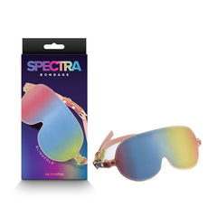 Displayed alongside its packaging is the Spectra Bondage Blindfold - Rainbow, a vibrant blindfold made from PU leather with a coordinating strap. The packaging mirrors the blindfold's design and showcases the "SPECTRA BONDAGE" text in colorful letters against a dark purple background, making it ideal for BDSM play.