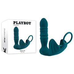 A teal prostate massager called the Playboy Pleasure BRING IT ON Butt Plug and Cock Ring, featuring a ring handle and ribbed design, is showcased alongside its packaging box. The box, emblazoned with "Playboy Pleasure," highlights the product along with branding and details. This versatile device can also be used as a cock ring for enhanced pleasure.
