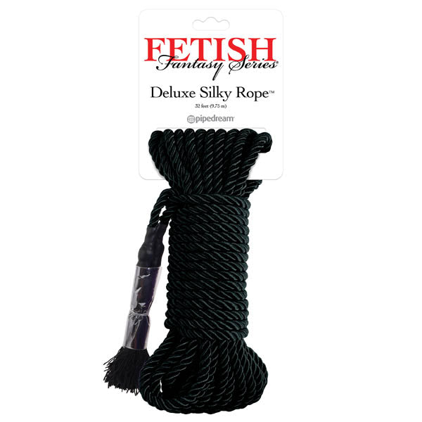 The image showcases a coiled black silky rope under the label "Fetish Fantasy Series Deluxe Silky Rope - Black" by Pipedream. Perfect for Shibari-style rope bondage, the 32-foot (9.75 m) rope ends in frayed strands and is bundled using clear plastic wrap near one end.
