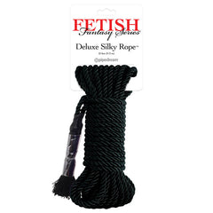 The image showcases a coiled black silky rope under the label "Fetish Fantasy Series Deluxe Silky Rope - Black" by Pipedream. Perfect for Shibari-style rope bondage, the 32-foot (9.75 m) rope ends in frayed strands and is bundled using clear plastic wrap near one end.