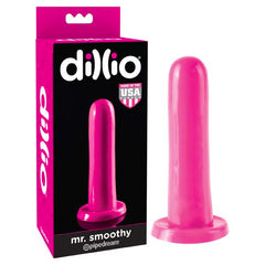 A hot pink, cylindrical adult toy with a rounded end and a suction-cup base is displayed next to its black and pink packaging. The box is labeled "Dillio Mr. Smoothy Dildo - Pink" and features a "Made in the USA" badge.
