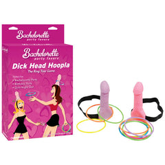 A product image showcasing the novelty party game "Bachelorette Party Favors Dick Head Hoopla - Ring Toss Game." The set features two head straps with attached pink and purple foam penis shapes, along with several colorful rings. The pink packaging promotes it as one of the ultimate bachelorette party favors.