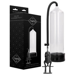 Image of a "Pumped Deluxe Beginner Penis Pump - Clear." The photo features the pump, comprising a transparent cylinder connected to a black, flexible hose with an attached hand pump. The packaging displays an image of the pump along with branding and product information for effective penis enlargement.