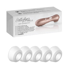 The image showcases the Satisfyer Pro 2 Climax Tips, a personal massager in a bronze color. Beside the box, there are four white replacement silicone tips laid out in a row. The product box features text in multiple languages and an image of the massager.