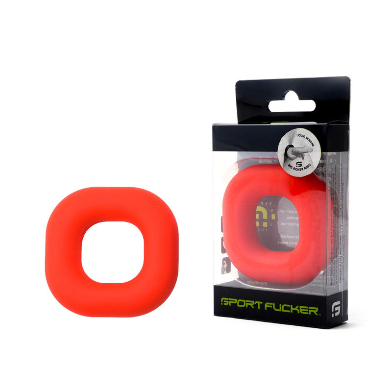 The Sport Fucker Big Boner Cock Ring, crafted from high-quality liquid silicone, is ergonomically shaped with a smooth, rounded square design. Displayed in red next to its black and transparent packaging, the package prominently features the brand name "Sport Fucker" and showcases the same ring inside.