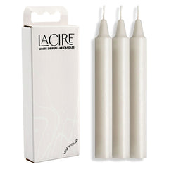 The image features a box labeled "LaCire Drip Pillar Candles - White" on the left and three upright white cylindrical candles on the right. Crafted from body-safe paraffin wax, these sensual drip candles are ideal for temperature play. The box is predominantly white with a minimalist design and text.