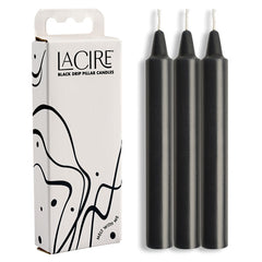 Image of a package of LaCire Drip Pillar Candles - Black, made from body-safe paraffin wax. The white box features black abstract designs and text that reads "LaCire Drip Pillar Candles - Black." Beside the box, three sensual drip candles stand upright, perfect for temperature play.