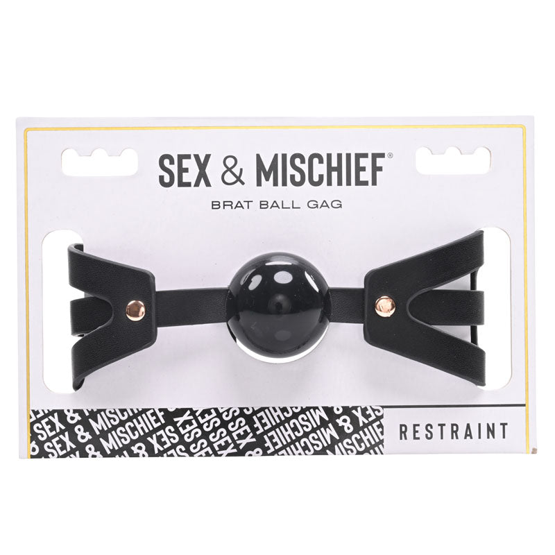 The "Sex & Mischief Brat Ball Gag" is packaged with a soft ball gag and an adjustable buckle. The white and black packaging features the product name in bold lettering and includes a clear display window to showcase the ball gag. The bottom of the package reads "Restraint.