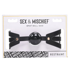 The "Sex & Mischief Brat Ball Gag" is packaged with a soft ball gag and an adjustable buckle. The white and black packaging features the product name in bold lettering and includes a clear display window to showcase the ball gag. The bottom of the package reads "Restraint.