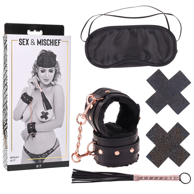 Image of the "Sex & Mischief Brat Kit" from Sportsheets, featuring wrist restraints, an eye mask, two black pasties, and a small mini flogger. The packaging includes an image of a person wearing the items on the front.