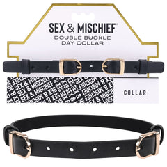 An image of the Sex & Mischief Double Buckle Day Collar made of black faux leather, featuring two gold-colored adjustable buckles and several sizing adjustment holes. It is displayed against its packaging, which has the brand name and a black-and-white background pattern.