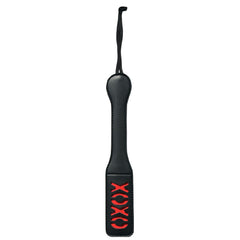 The Sex & Mischief XOXO Paddle - Black is a vinyl paddle featuring a sexy "XOXO" design cut out near the end. It has a wider end for impact and a narrow handle with a black wrist strap for grip.
