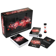 A boxed card game titled "You And Me - Couples Game" is shown. The image includes two card decks, some cards face up displaying male and female symbols, and an hourglass timer with red sand—the perfect romantic game for couples. The background features a heart-themed design.