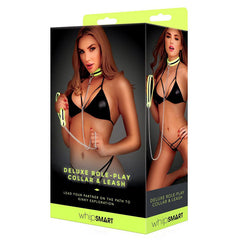 Packaging for the WhipSmart Glow Deluxe Role-Play Collar and Leash. The box features a model wearing a black bikini and showcasing the neon yellow collar and glow-in-the-dark leash set. The background is black, and the brand name is at the bottom of the box.